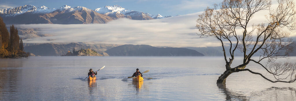 People kayaking on Lake Wānaka with scenic backdrop in New Zealand