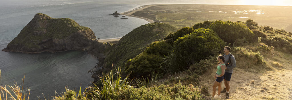 Couple admiring scenic views on the sea from the top of Ōmanawanui walking track, Auckland